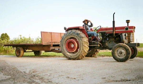 Farm, tractor and agriculture with happy woman farmer driving a vehicle on farm for sustainability, growth and development in a sustainable and green environment. Farming crops in the harvest season.