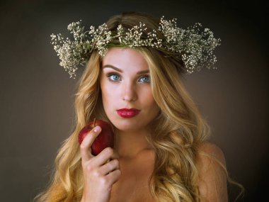 Go on, one bite will do you good. Studio shot of a gorgeous young woman eating a red apple against a dark background