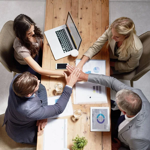 Success is a joint effort. High angle shot of a group of businesspeople joining their hands together in unity