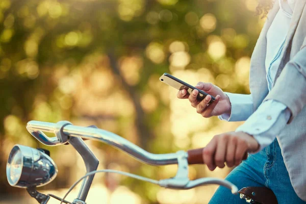 Hands of a girl, on bicycle and using smartphone app, social media and doing a internet or web search closeup. Woman uses her bike for health, fun or travel by cycling to park, work and home or city.