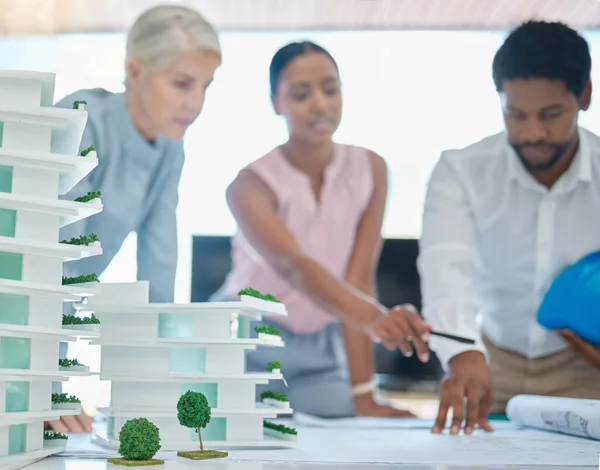 Architect or engineer team planning and designing a building in a meeting in the office or boardroom. City development planner or architecture group with a 3d model and working on a strategy.