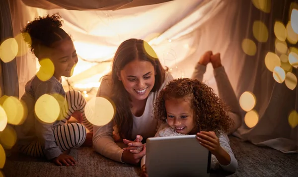 Mother, children and tablet with happy family watching online tv, learning with education games and reading ebook at night at home. Internet and enjoying live stream movies with cartoon subscription.