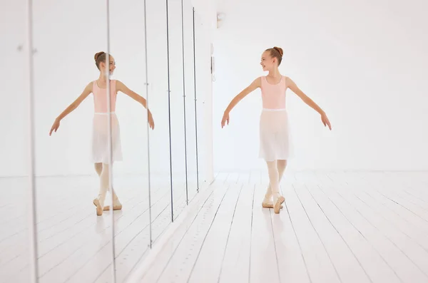 Fitness, exercise and the art of ballet, young dancer watching herself in a mirror. Happy, confident and learning to love dance and dancing the lifestyle. A ballerina girl training alone in a studio