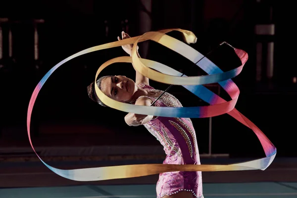 Woman dancing with ribbon in concert in arena, dancer doing creative, artistic and cardio dance and training a performance in dark studio. Girl gymnast doing sport workout and strong in competition.