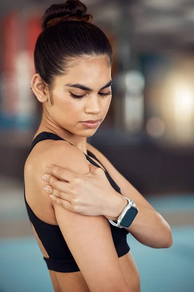 Injury, hurt and shoulder pain for a female athlete holding her painful arm at the gym. Active, fit and athletic woman suffering from muscle inflammation due to an exercise or workout.