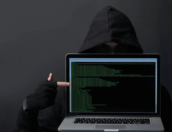 See your data It belongs to me now. an unidentifiable computer hacker holding up a laptop against a dark background