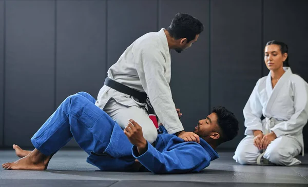 Karate, fitness and martial arts instructor teaching a lesson on fighting and defense training at a gym or indoor center. Diverse sporty student learning how to be safe in an attack with tough coach.
