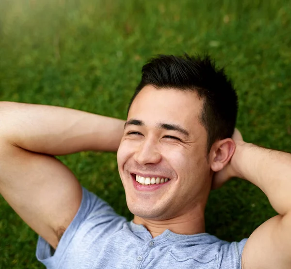 Time to chill out and enjoy the weekend. a handsome young man relaxing on the grass outdoors