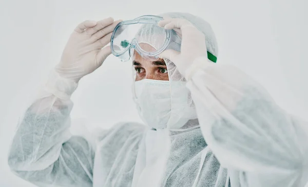 Covid, healthcare worker with safety protection clothing during first virus outbreak. A medical research professional in a hazmat suit and goggles preparing for work and staying safe during pandemic.