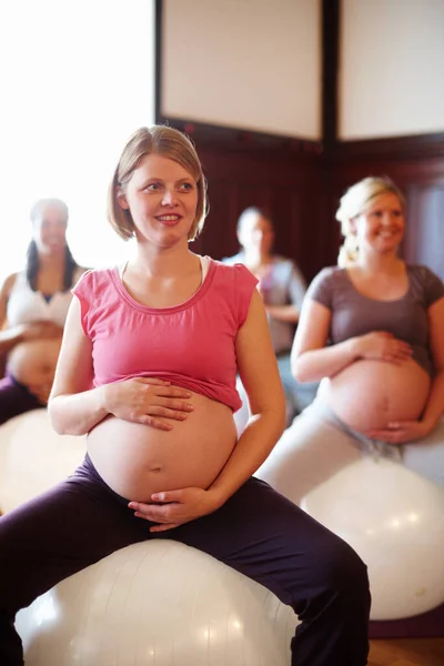 Exercise class, pregnant mother fitness and women workout at maternity wellness care studio. Happy woman with pregnancy belly on gym ball with the motivation for a strong and healthy body