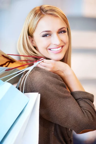 Fashion, sale and shopping woman or customer is happy and excited holding bags at a store. Discount, offer and deal for smiling female in retail shop at the mall spending money on style at an outlet.