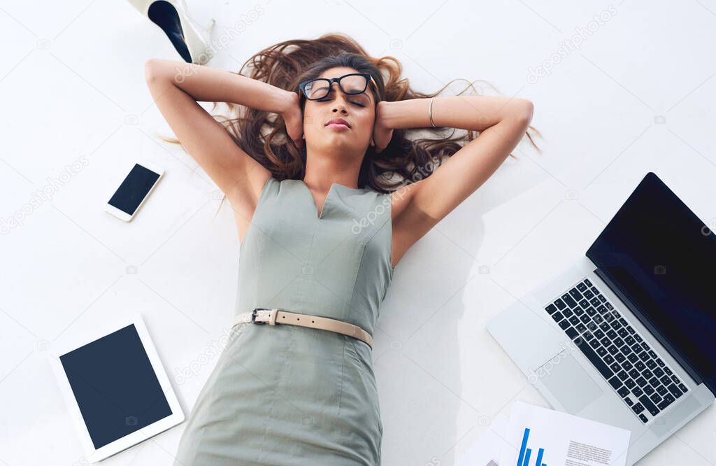 Stress has hit her hard. High angle shot of a young businesswoman lying on her office floor