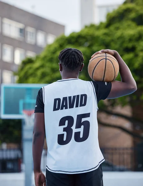 Basketball, sports and fitness exercise of a sport player on an outdoors court for a workout. Back of a strong man and athlete with a ball ready to start cardio, active or game match training outside.