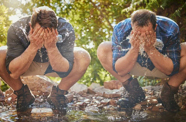 Hiking men splash face with water for cool, relax and cleaning dirt when trekking on rock or hike in countryside forest. Earth, freedom after camping in nature and travel along mountain river or lake.