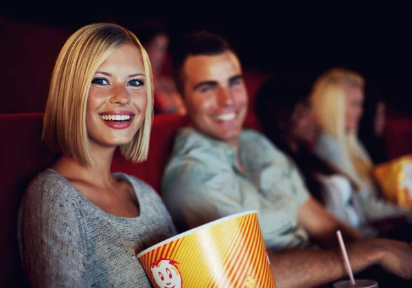 Movie, popcorn and smile with woman on a date with man at cinema interior or theater event. Happy, film or show screen with couple eating snacks and watching together at night time.