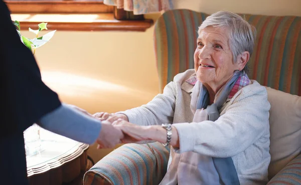 Nurse helping old woman holding hands in retirement home.