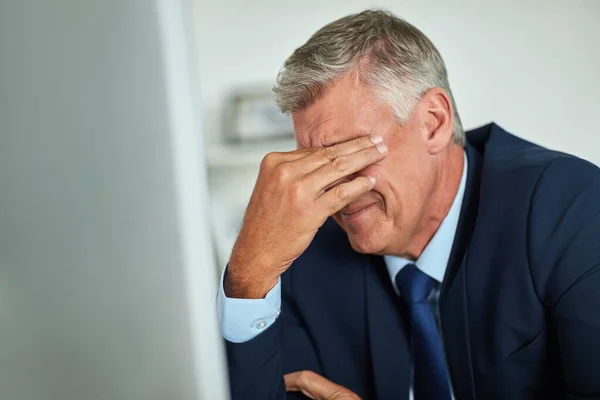 Seriously. a mature businessman looking frustrated while working on his computer in the office