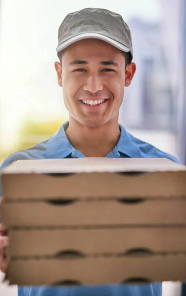 From our ovens to your door. Portrait of a happy deliveryman holding a stack of pizza boxes