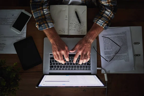 The freedom to do business on his own time. High angle shot of an unidentifiable programmer using his laptop in the office