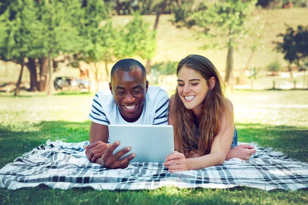 Good days are even better when theyre shared. a young couple relaxing on a blanket outdoors and using a digital tablet