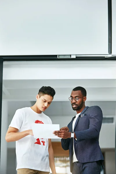 Having an impromptu pitch. two colleagues reading a document together at work