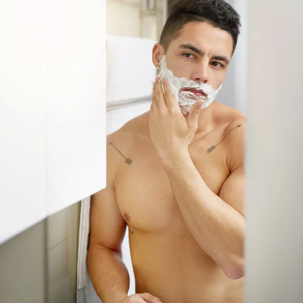 I never shave without shaving cream. a young man applying shaving cream to his face