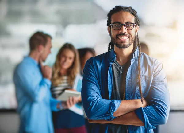 My team is the key to my success. Portrait of a handsome young designer standing in the office with his colleagues in the background