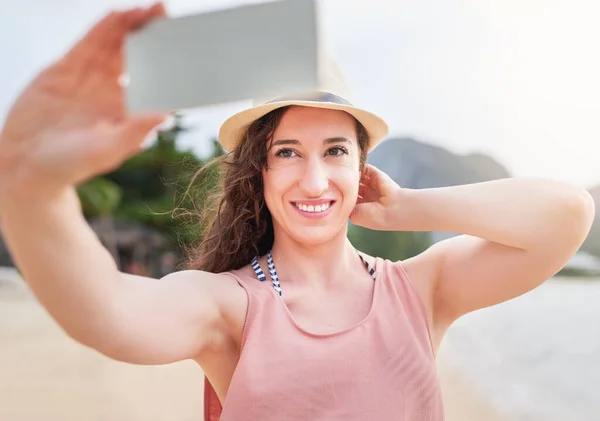 Wish you were here. a happy young woman taking a selfie with her phone on a tropical beach
