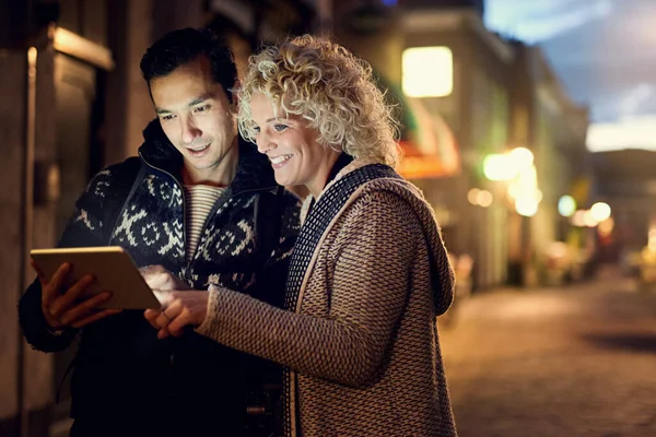 Check this out. an affectionate young couple looking at photographs on their tablet while on vacation