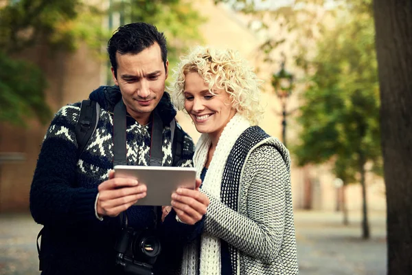 Lets take a look at these photos. an affectionate young couple looking at photographs on their tablet while on vacation