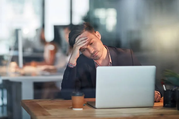 Maybe its time to look for a new job. a young businessman with a headache trying to get his work done in the office