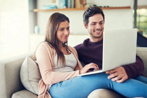 What series would you like to watch dear. a cheerful young couple using a laptop while relaxing on the sofa together at home