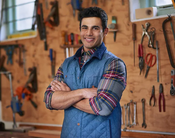 DIY Im your guy. Portrait of a happy handyman standing in his workshop with his arms folded