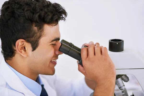Just what he was searching for. a lab technician using a microscope while sitting in a lab