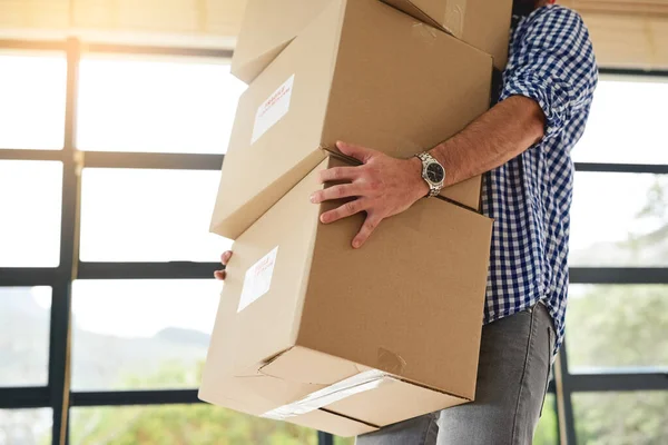 I hope I dont drop this. an unidentifiable man carrying a pile of boxes while moving house