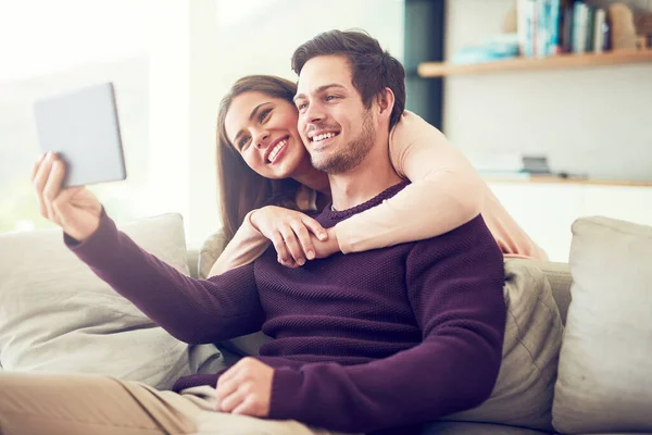 Catching up with some old friends online. a smiling young couple using a digital tablet while relaxing on the sofa at home