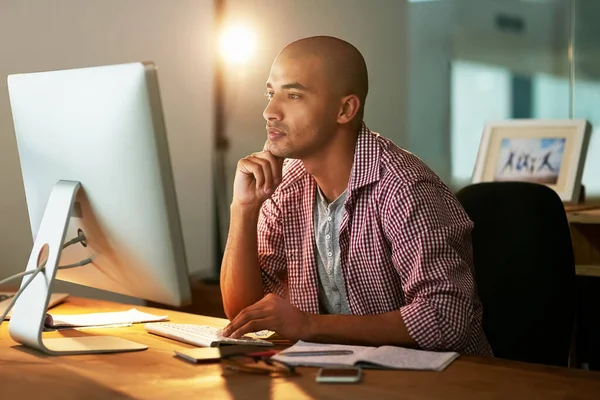 Figuring out how to execute all his brilliant ideas. a young designer working late in an office