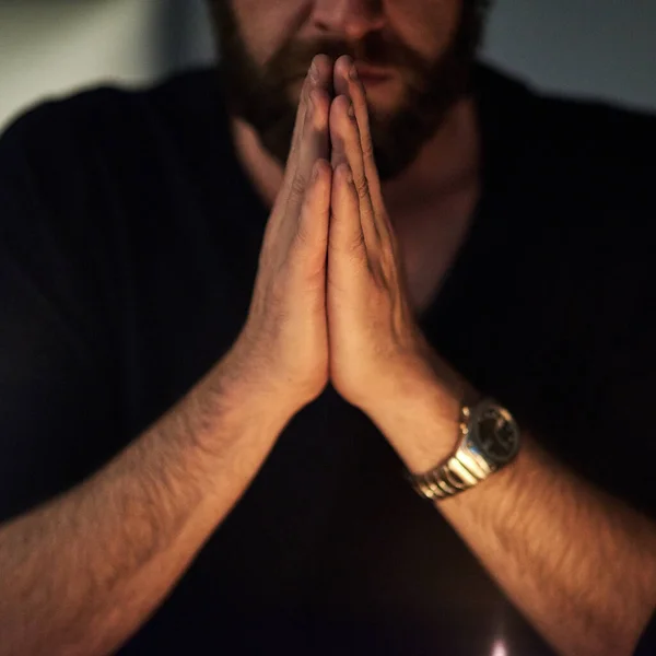 Praying hard for redemption. Closeup shot of a man with his hands clasped in prayer