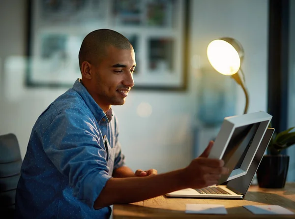 Remember what keeps you going. a young businessman looking at a photo frame while working late at his office desk