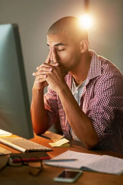 These late nights are beginning to wear me out. a young designer looking stressed out while working late in an office