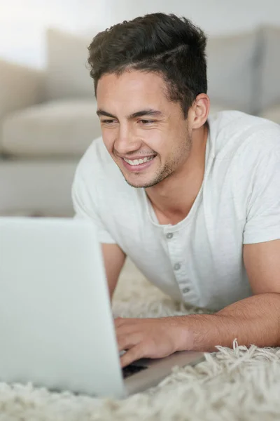 Connected living in comfort. a relaxed young man using a laptop on the floor at home