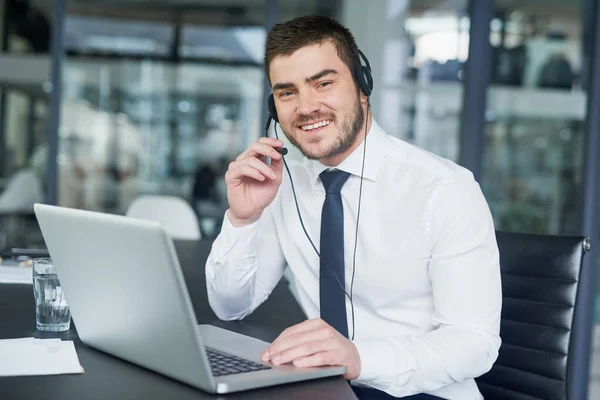 Here to offer support. Portrait of a young customer service representative wearing a headset while sitting at his workstation in an office