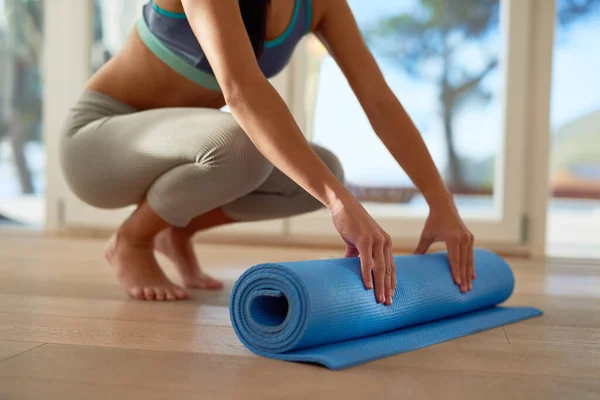 Roll out fatigue and roll in fitness. an unidentifiable woman rolling a yoga mat
