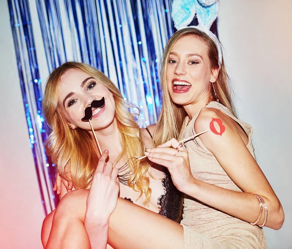Ladies night done right. two beautiful young women having fun with props in a photobooth