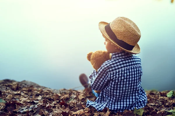 Teddy makes me feel safe. a little boy sitting in the forest with his teddy bear