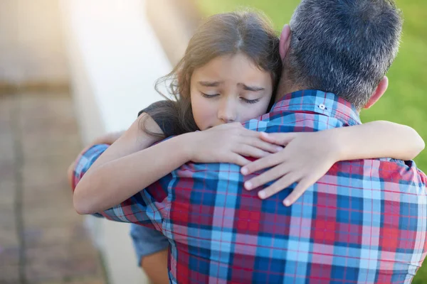 Daddys hugs make everything better. a sad little girl being consoled by her father at home
