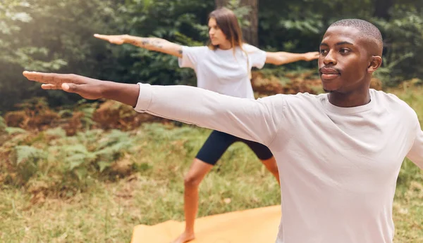 Couple, nature and yoga of a man and woman in workout exercise for the mind, body and spirit outdoors. Interracial fitness people together in relaxing exercises, stretching and balance lifestyle