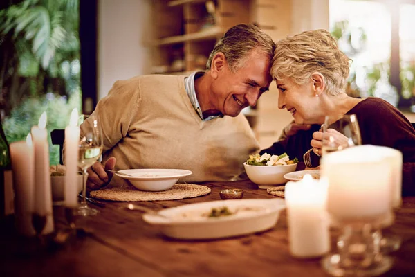 Love the way you make me laugh. an elderly couple enjoying a meal and wine together at home