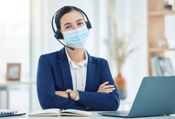 Covid, telemarketing and woman with mask portrait at a corporate work building in the pandemic. Help desk worker at table with medical face protection from coronavirus transmission with staff