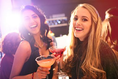Our favorite weekend party spot. Portrait of two young women drinking cocktails at a party clipart